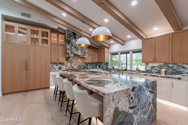 kitchen with hanging light fixtures, light stone countertops, lofted ceiling with beams, and a center island