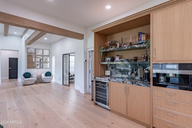 bar with light brown cabinetry, beam ceiling, beverage cooler, and light wood-type flooring