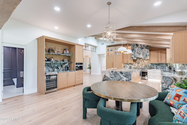 dining space with beverage cooler, sink, a notable chandelier, vaulted ceiling, and light hardwood / wood-style flooring