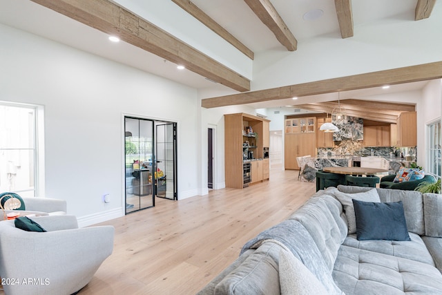 living room with an inviting chandelier, beamed ceiling, light hardwood / wood-style flooring, and high vaulted ceiling