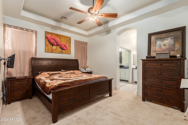 carpeted bedroom featuring ceiling fan, a raised ceiling, and connected bathroom