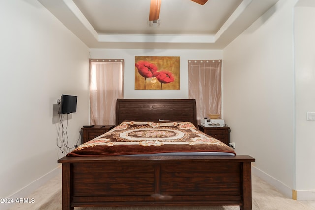 bedroom featuring ceiling fan, a raised ceiling, and light carpet