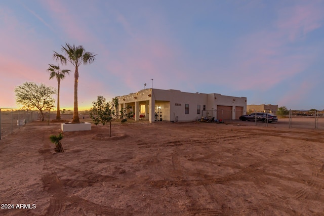 back house at dusk featuring a garage