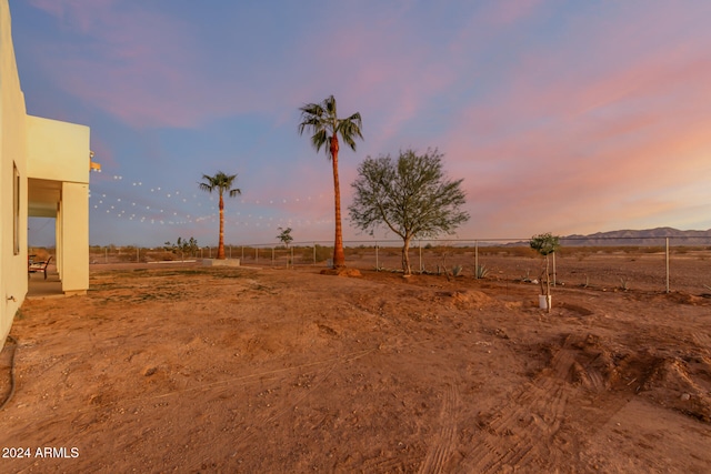 yard at dusk featuring a mountain view and a rural view