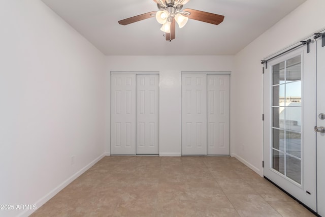 unfurnished bedroom featuring access to outside, ceiling fan, and two closets