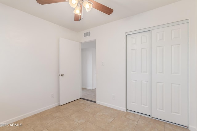 unfurnished bedroom featuring ceiling fan, light tile patterned flooring, and a closet