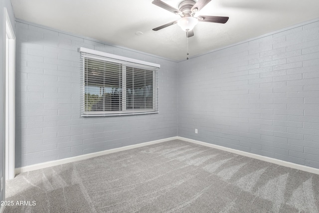 unfurnished room with carpet flooring, ceiling fan, and brick wall