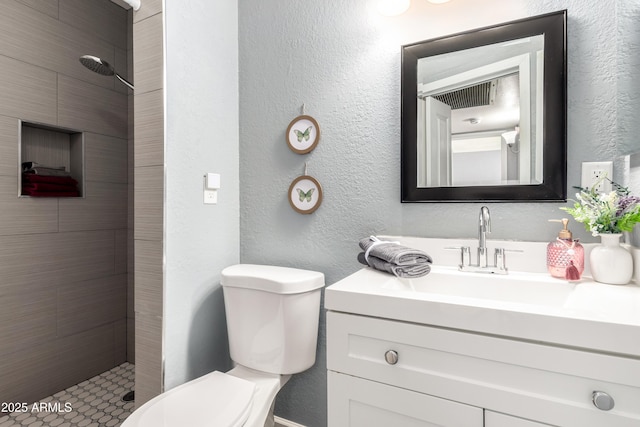 bathroom featuring tiled shower, vanity, and toilet