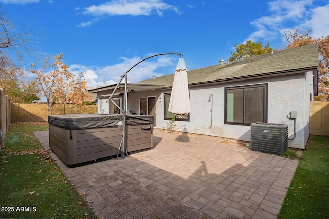 rear view of property featuring central AC, a hot tub, and a patio