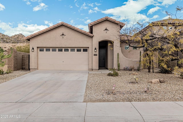 mediterranean / spanish home featuring a garage, concrete driveway, a tiled roof, fence, and stucco siding