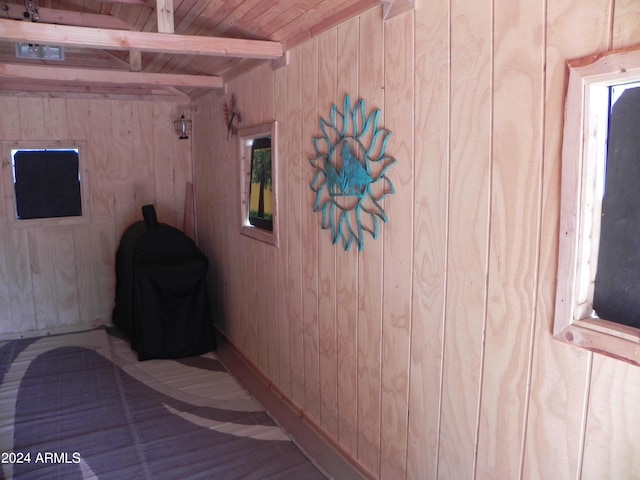 unfurnished bedroom featuring wood walls, wood ceiling, and beam ceiling