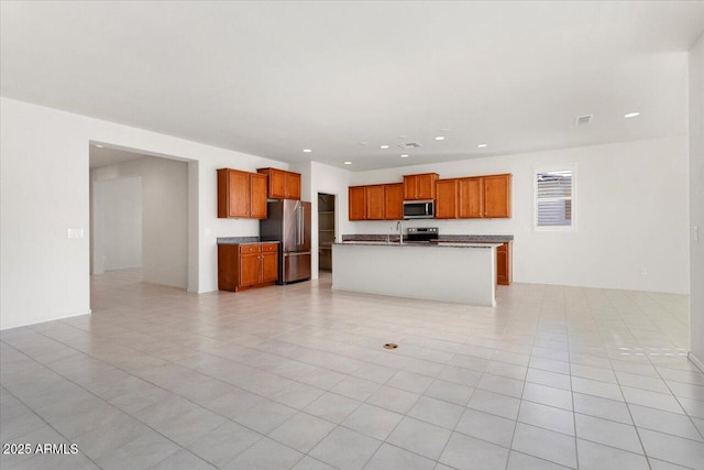 kitchen with stainless steel appliances, light tile patterned floors, sink, and a kitchen island with sink