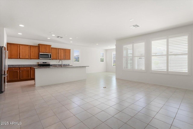 kitchen with appliances with stainless steel finishes, sink, a center island with sink, and light tile patterned floors