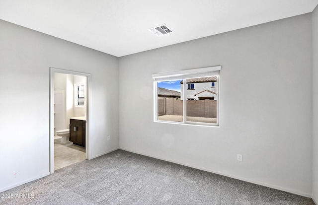 unfurnished bedroom featuring light carpet, baseboards, visible vents, and connected bathroom