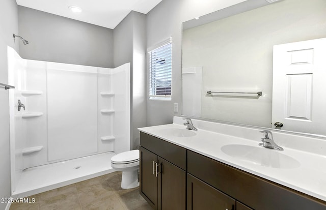 bathroom with double vanity, a stall shower, a sink, and toilet