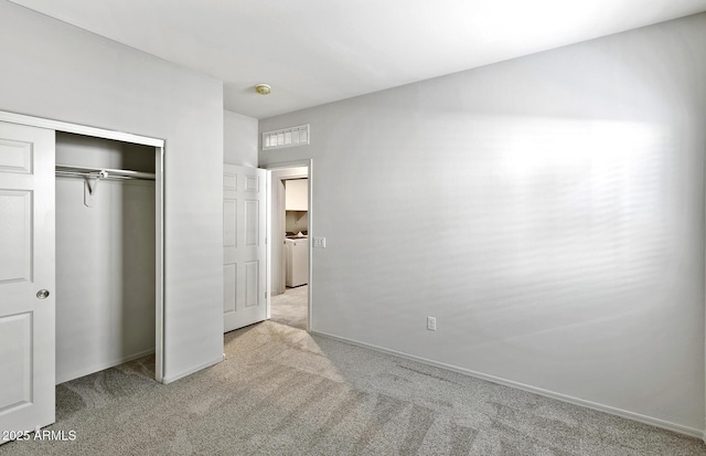 unfurnished bedroom featuring baseboards, visible vents, light colored carpet, washer / clothes dryer, and a closet