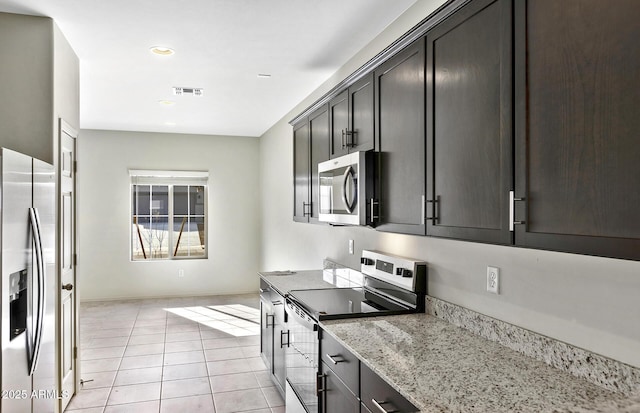 kitchen with light stone counters, stainless steel appliances, visible vents, light tile patterned flooring, and dark brown cabinets