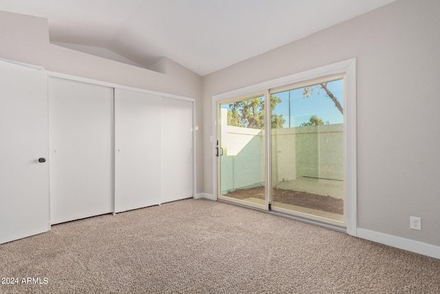 unfurnished bedroom featuring lofted ceiling, access to exterior, and carpet