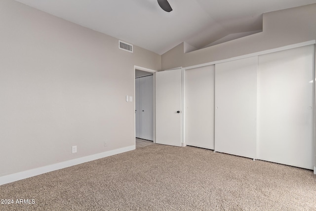 unfurnished bedroom featuring light carpet, ceiling fan, a closet, and vaulted ceiling