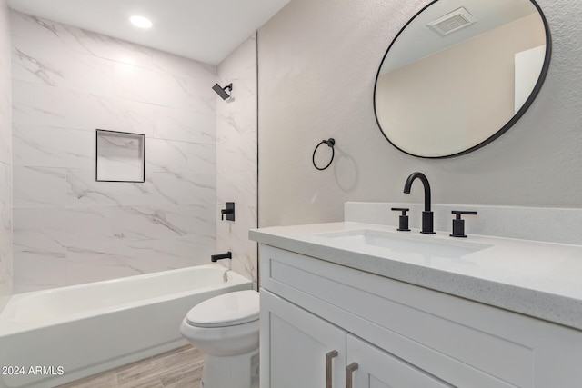 full bathroom with wood-type flooring, tiled shower / bath combo, vanity, and toilet