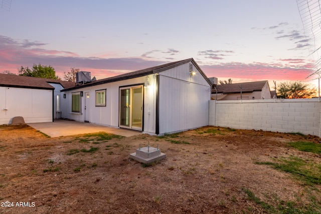 back house at dusk with a patio area