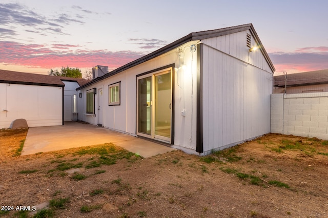 back house at dusk featuring a patio area