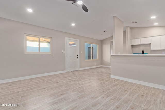 unfurnished living room featuring lofted ceiling, ceiling fan, and light hardwood / wood-style floors