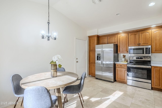 kitchen featuring vaulted ceiling, appliances with stainless steel finishes, hanging light fixtures, and a notable chandelier