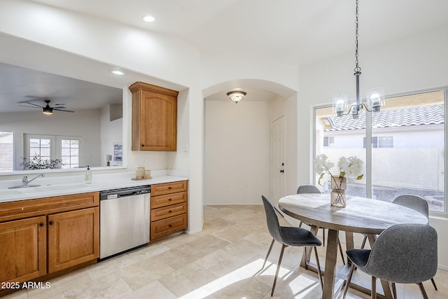 kitchen featuring stainless steel dishwasher, sink, hanging light fixtures, and ceiling fan with notable chandelier