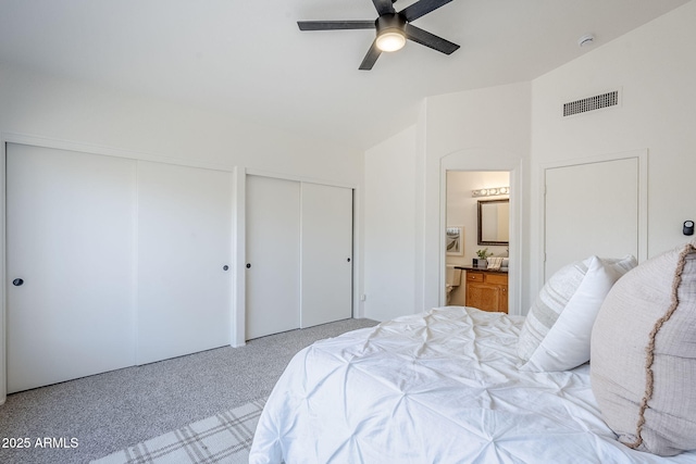 carpeted bedroom with connected bathroom, ceiling fan, lofted ceiling, and multiple closets