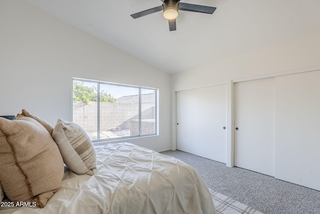 carpeted bedroom with vaulted ceiling, ceiling fan, and two closets