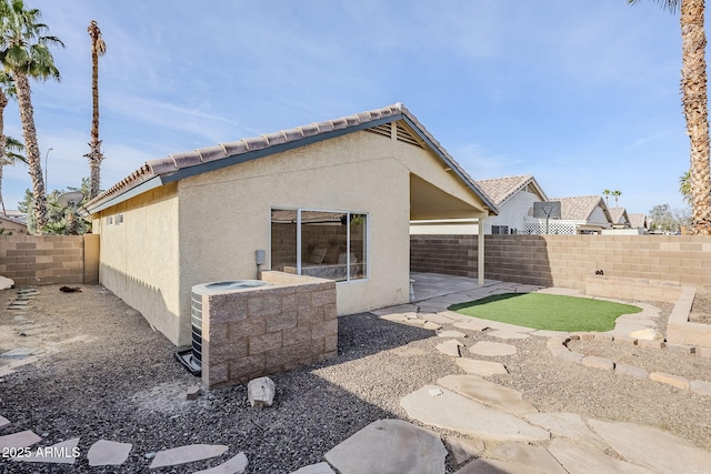 back of property with central AC unit and a patio