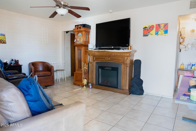 tiled living room with ceiling fan and a fireplace