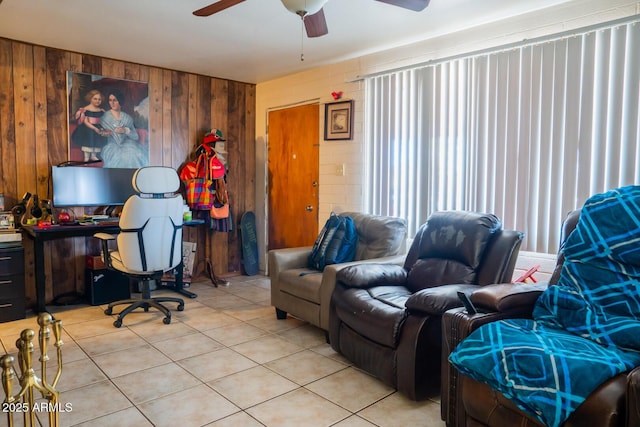 office with light tile patterned floors, ceiling fan, and wood walls