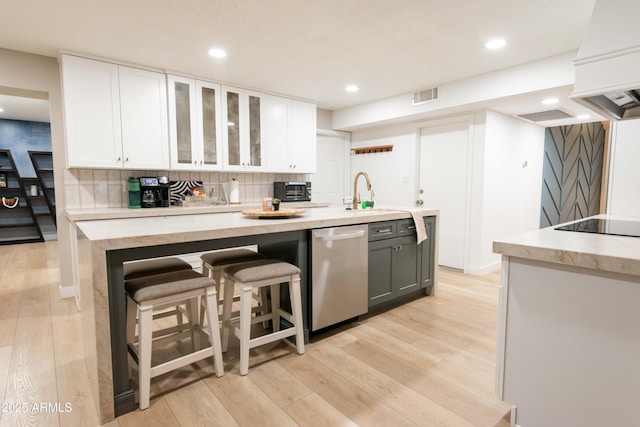 kitchen with a breakfast bar, gray cabinets, dishwasher, decorative backsplash, and white cabinets