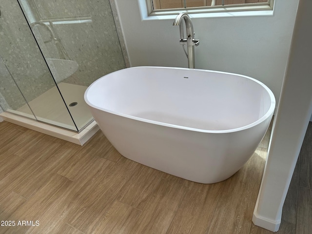 full bath featuring walk in shower, wood finished floors, and a soaking tub