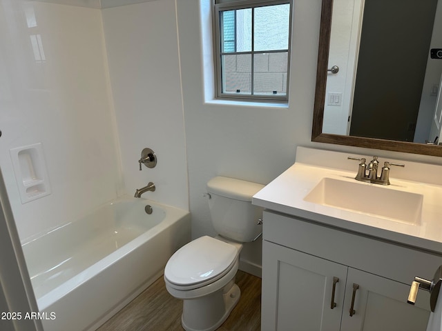 bathroom with toilet, vanity, wood finished floors, shower / washtub combination, and baseboards