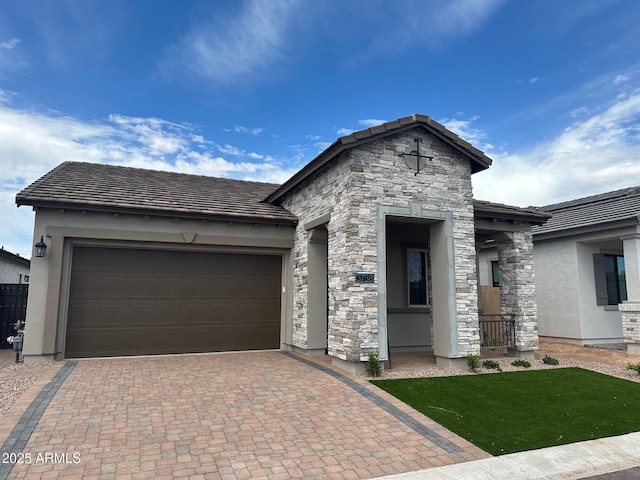 view of front of house with stucco siding, a garage, decorative driveway, a tiled roof, and stone siding