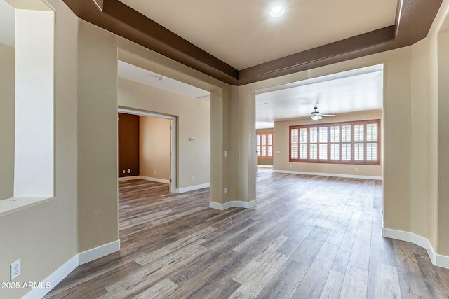 empty room with ceiling fan, wood finished floors, and baseboards