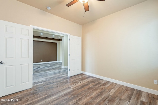 spare room featuring ceiling fan, wood finished floors, and baseboards