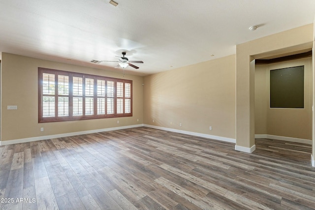 empty room featuring ceiling fan, visible vents, baseboards, and wood finished floors