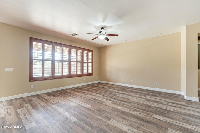 spare room with a ceiling fan, baseboards, visible vents, and wood finished floors