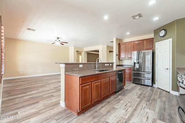 kitchen featuring visible vents, an island with sink, dishwashing machine, stainless steel refrigerator with ice dispenser, and a sink