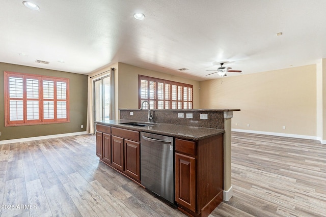 kitchen with dishwasher, open floor plan, a sink, and light wood-style floors