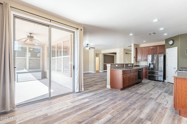 kitchen with black dishwasher, visible vents, light wood-style floors, a sink, and stainless steel fridge with ice dispenser