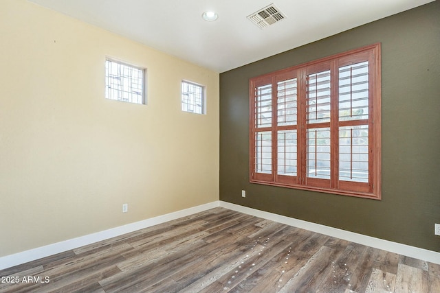 spare room with baseboards, visible vents, and dark wood finished floors