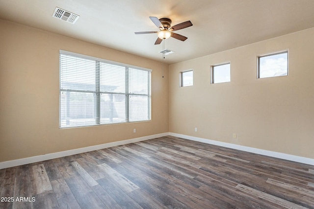 unfurnished room with dark wood-style floors, baseboards, visible vents, and a ceiling fan