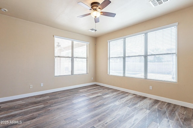 spare room featuring wood finished floors, visible vents, and baseboards