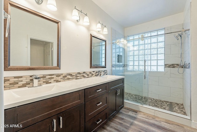 bathroom with a shower stall, decorative backsplash, a sink, and wood finished floors