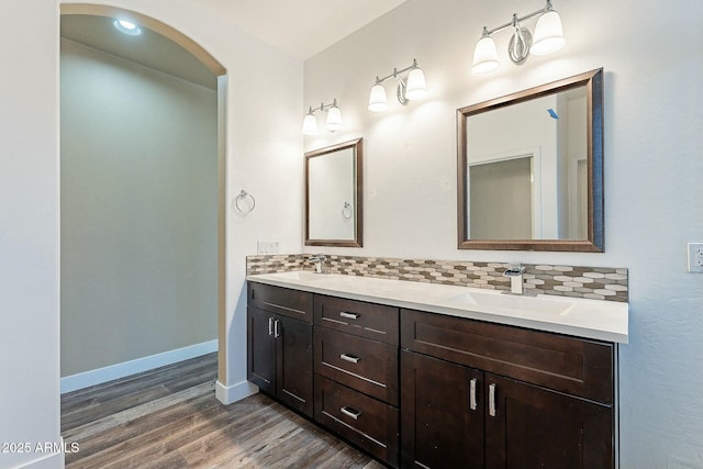 bathroom featuring wood finished floors, a sink, and decorative backsplash